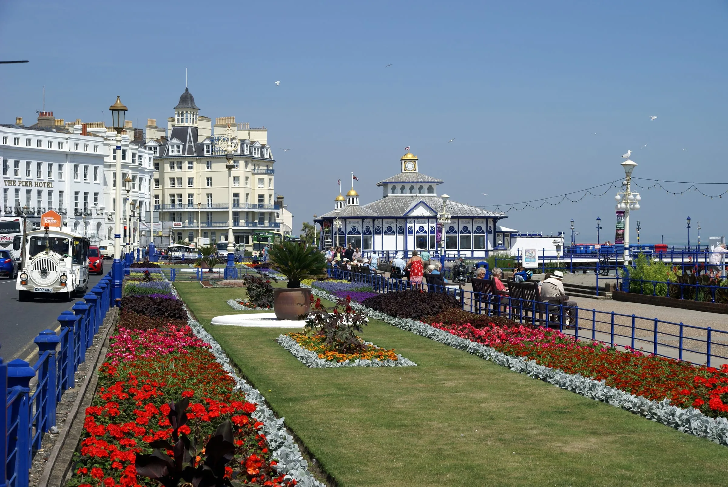 El paseo marítimo de Eastbourne con sus jardines floridos, el muelle y los hoteles blancos.