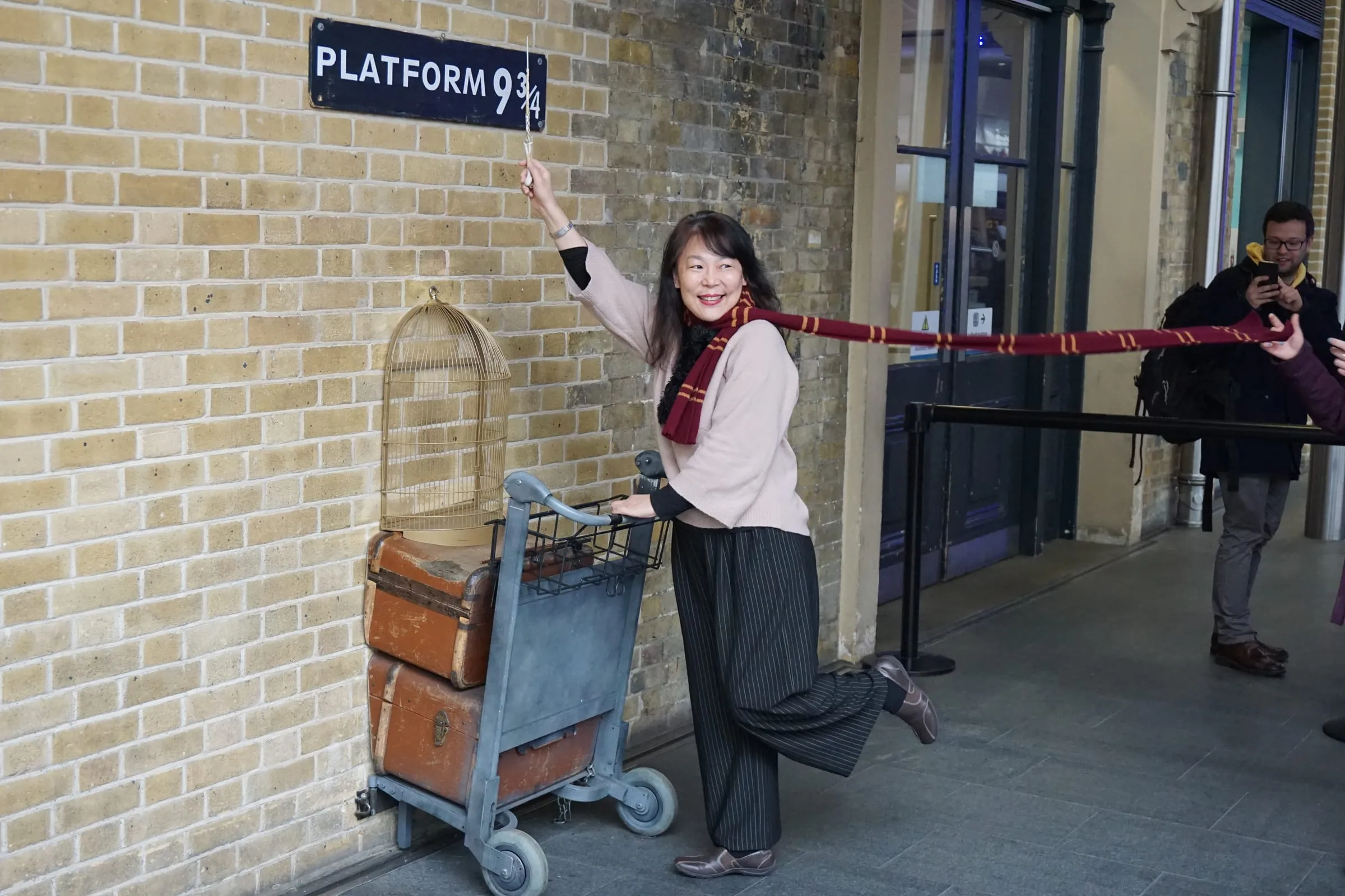 Una visitante posa con la bufanda de Gryffindor y el carrito del andén 9 ¾ en King’s Cross