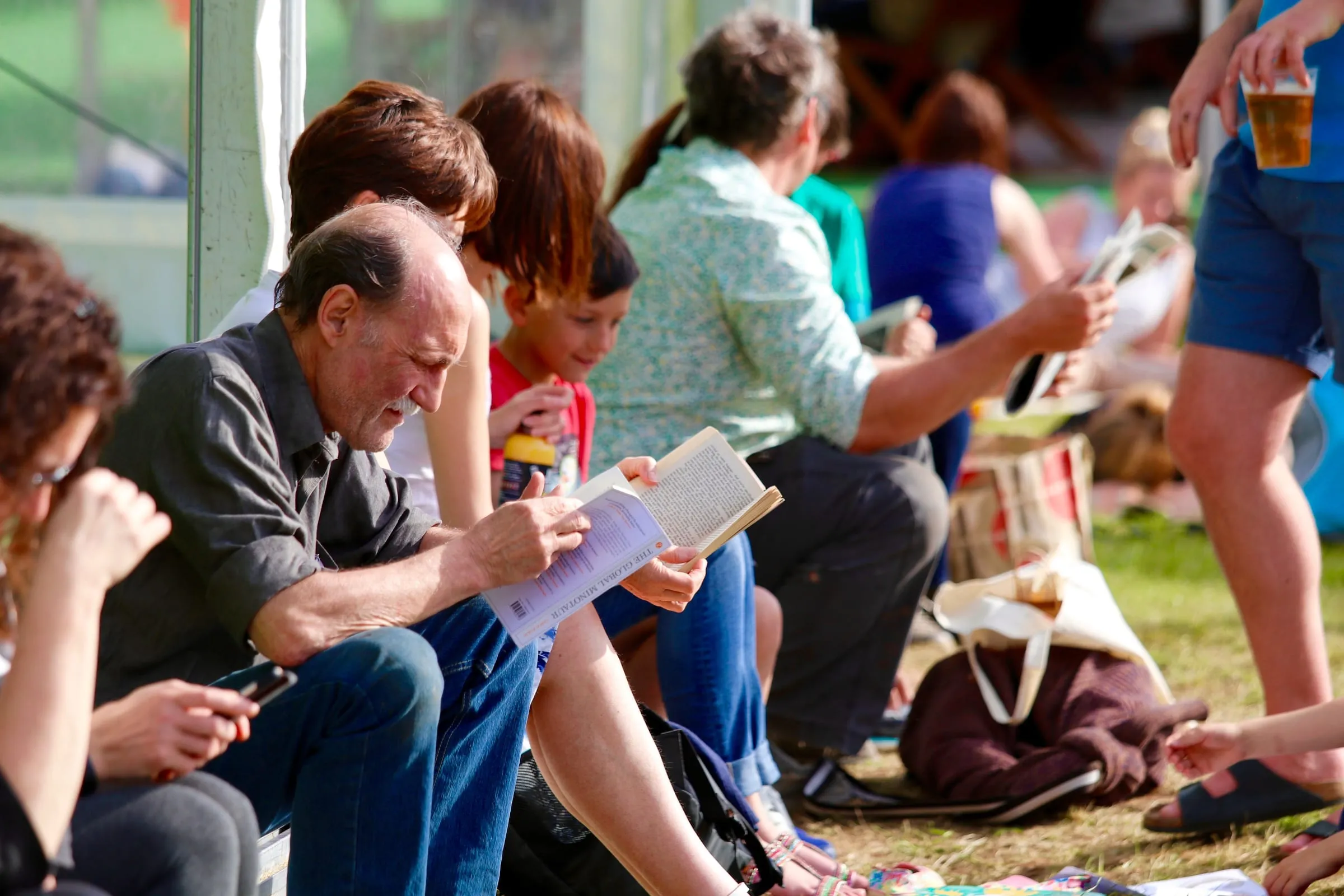 Público leyendo al sol entre carpas en el Hay Festival