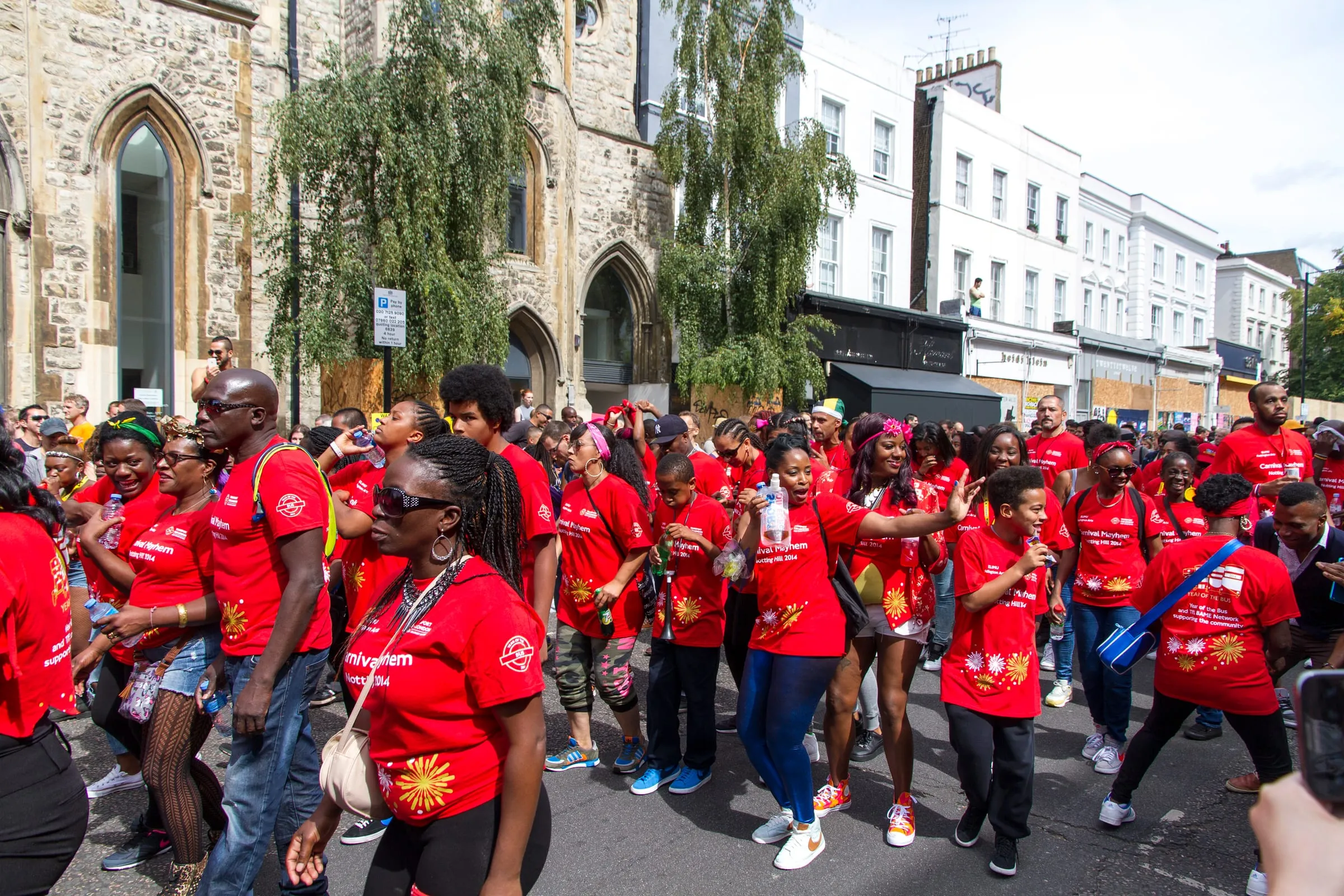 Una banda de carnaval con camisetas rojas desfilando por una calle de Notting Hill