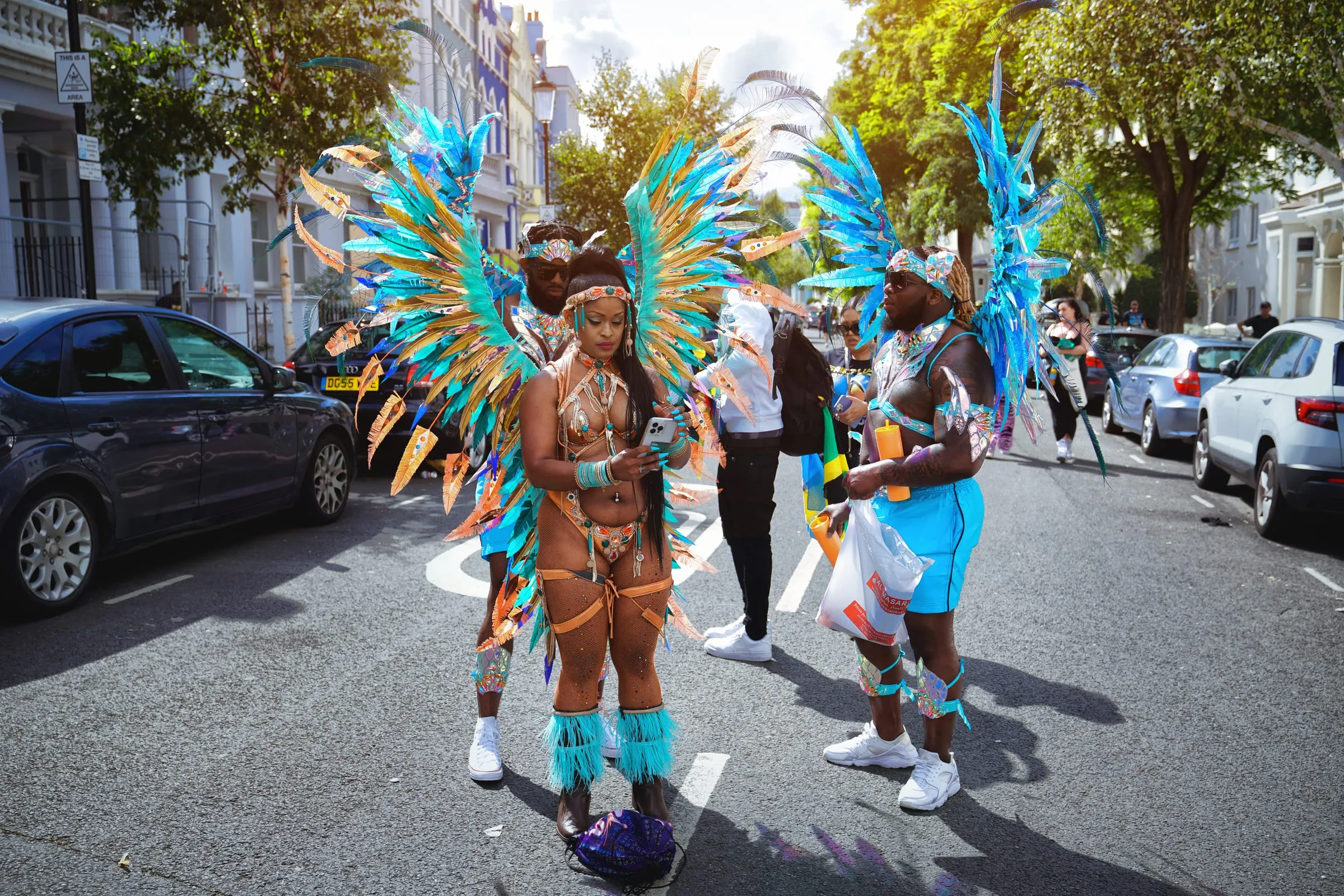 Bailarines con alas de plumas turquesa y naranja en una calle de Notting Hill durante el carnaval