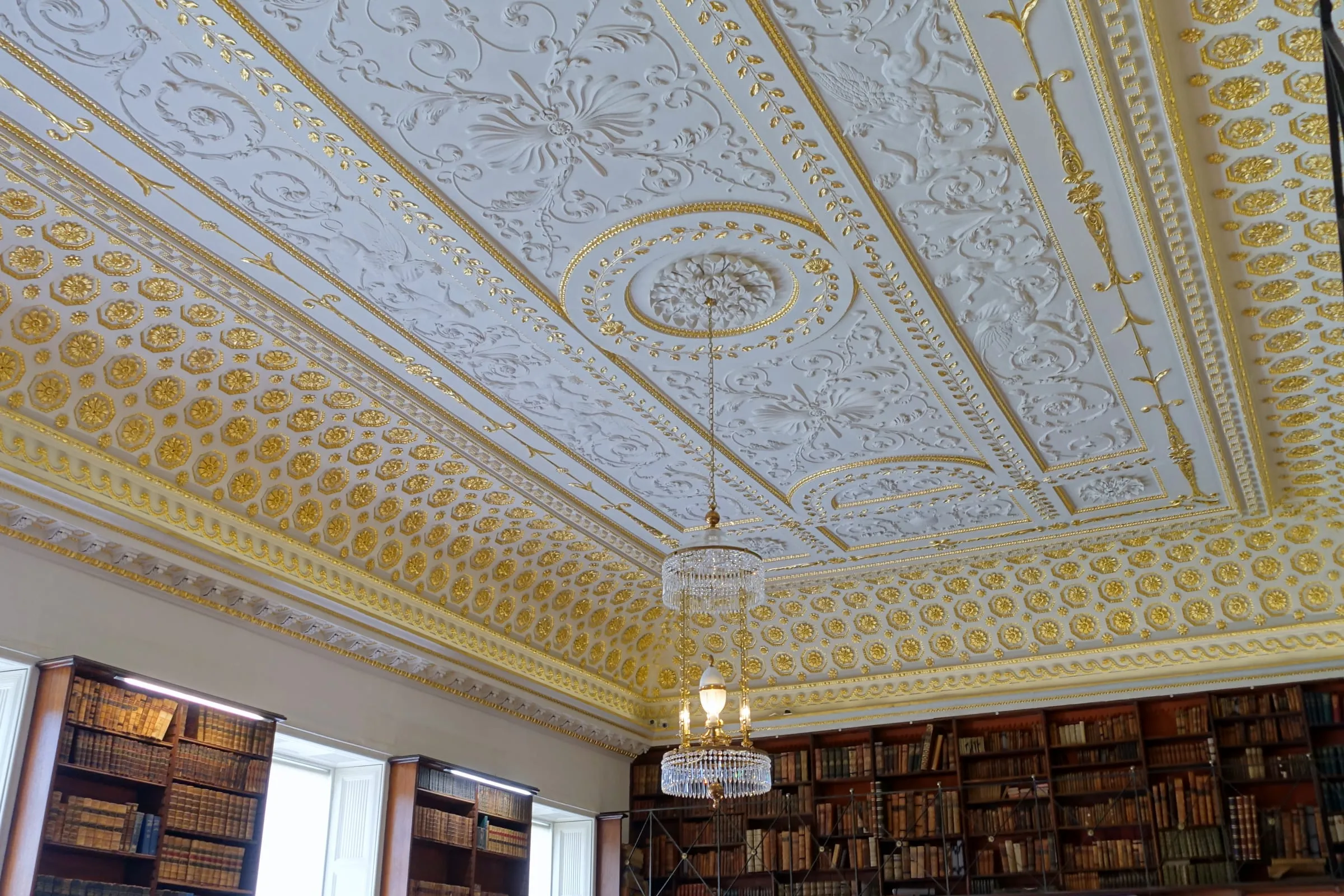 Biblioteca del internado con techo de estuco dorado y estanterías de madera