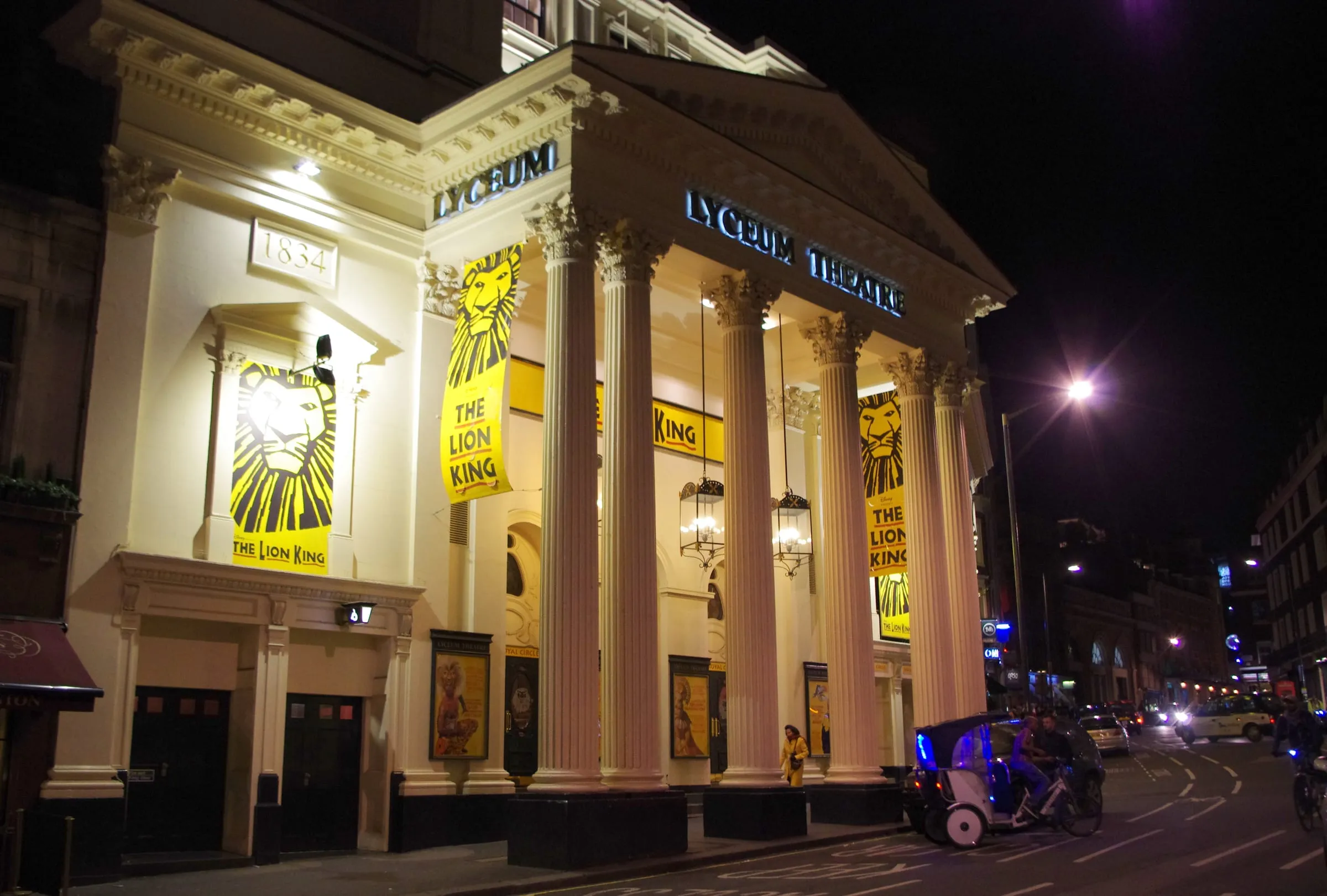 La fachada iluminada del Lyceum Theatre de noche, con los carteles de El Rey León