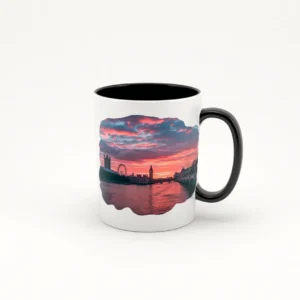 Taza de cerámica blanca con asa negra, decorada con una imagen de un atardecer sobre el horizonte de Londres, mostrando el London Eye y el Big Ben bajo un cielo colorido.